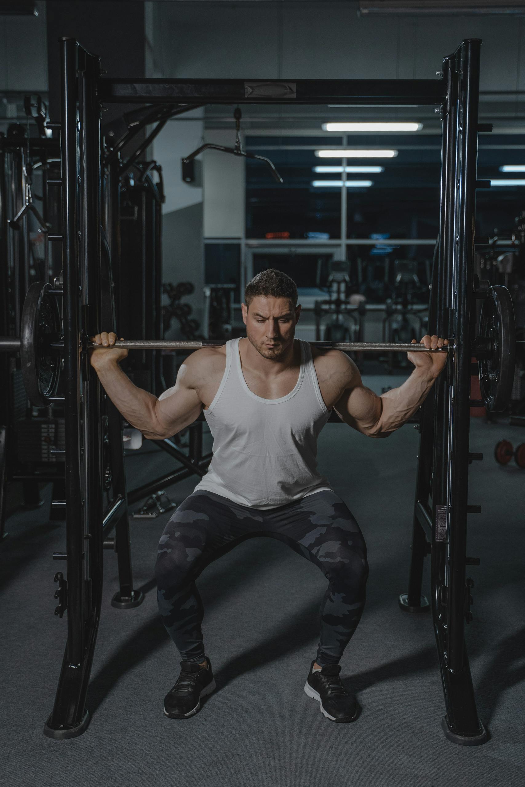Strong man performing squat with barbell in a gym, showcasing strength and fitness.